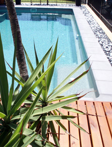 Terrasse piscine en bois avec margelle en pierre bleu